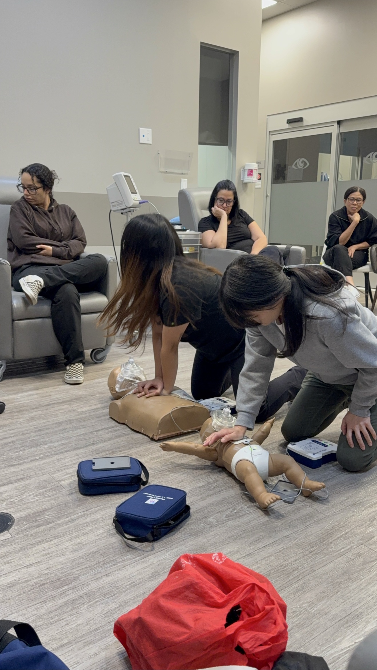 Students practising adult and infant CPR with AED trainers at an Academy for First Aid and Safety class