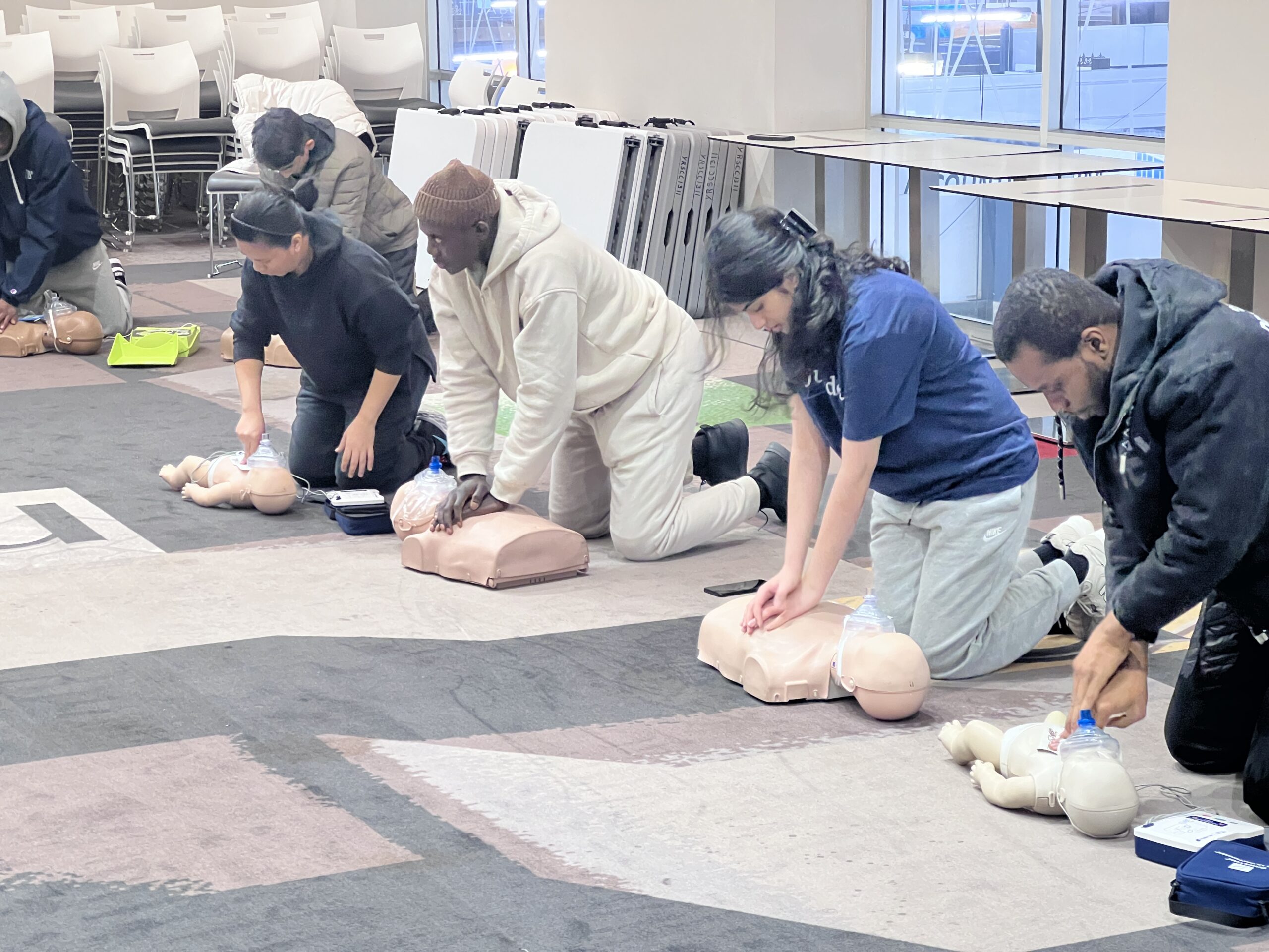 Students practising chest compressions on adult and infant manikins in an Academy first aid class