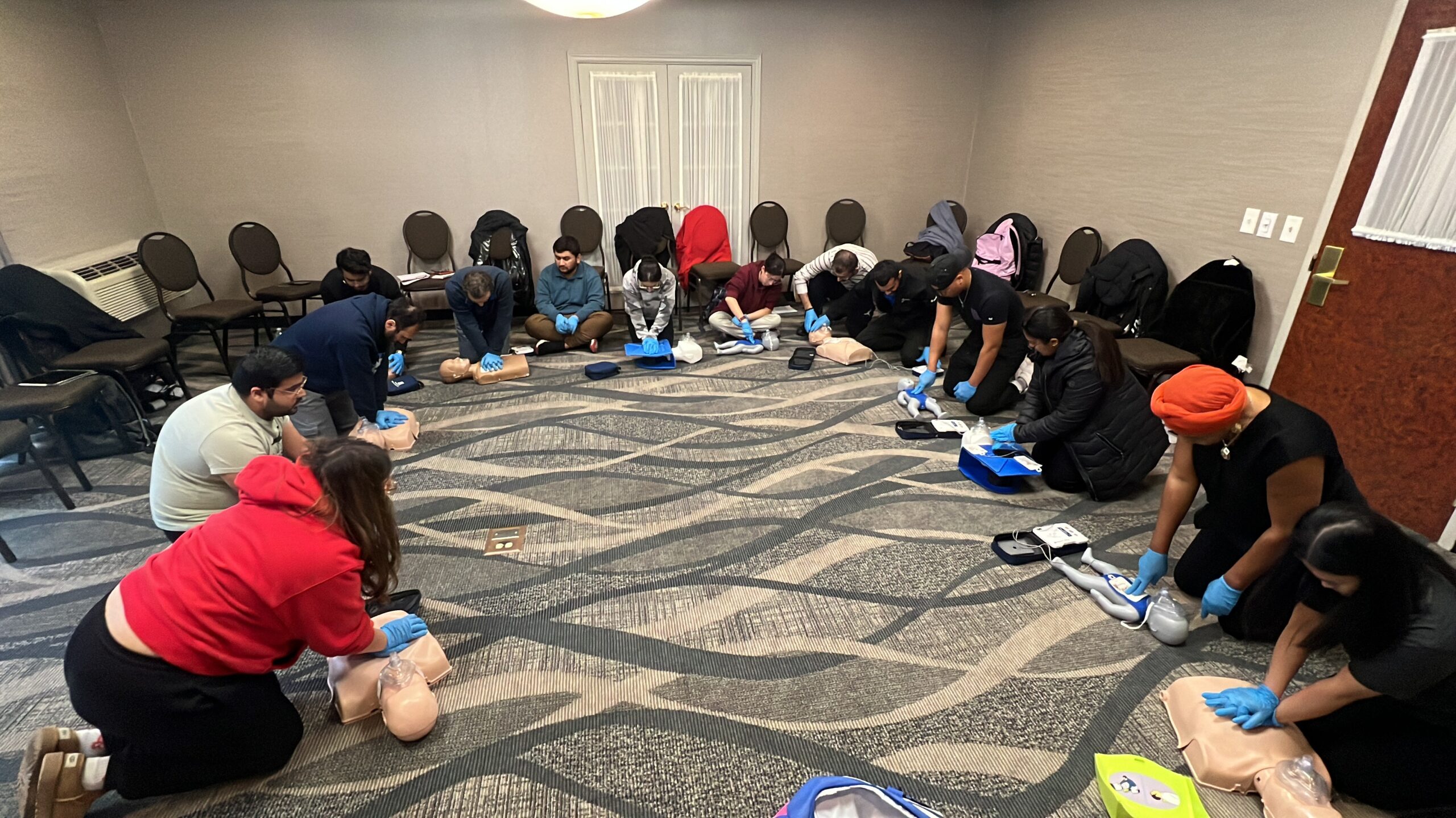 A large corporate group practising CPR in a circle at an Academy class
